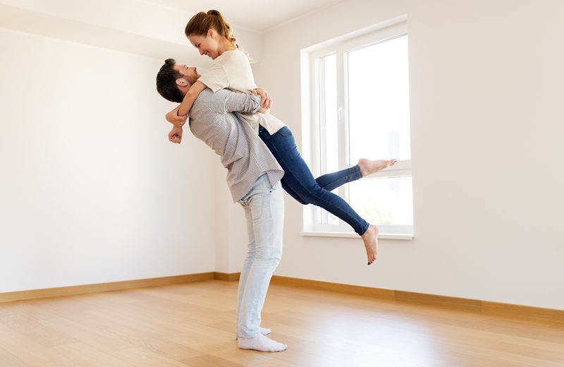 Homme et femme se sautent dans les bras dans leur maison neuve